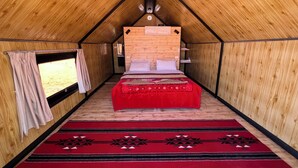 A tent-style room with a bed, a red carpet, and wooden walls.