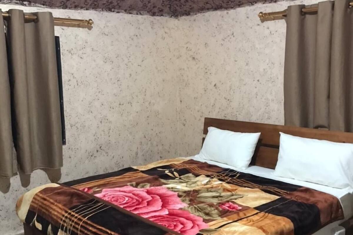 A bedroom with a bed, curtains, and patterned wallpaper.