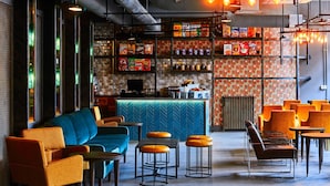A modern bar area with seating, shelves of snacks, and a bar counter. - New Road Hotel (London)