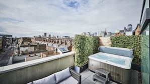 A rooftop terrace with a hot tub, seating area, and a view of the cityscape. - New Road Hotel (London)