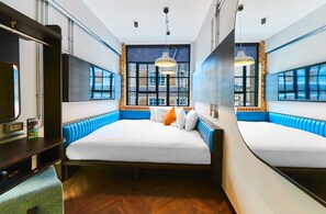 A modern hotel room with a large bed, a desk, and a view of the city through large windows. - New Road Hotel (London)
