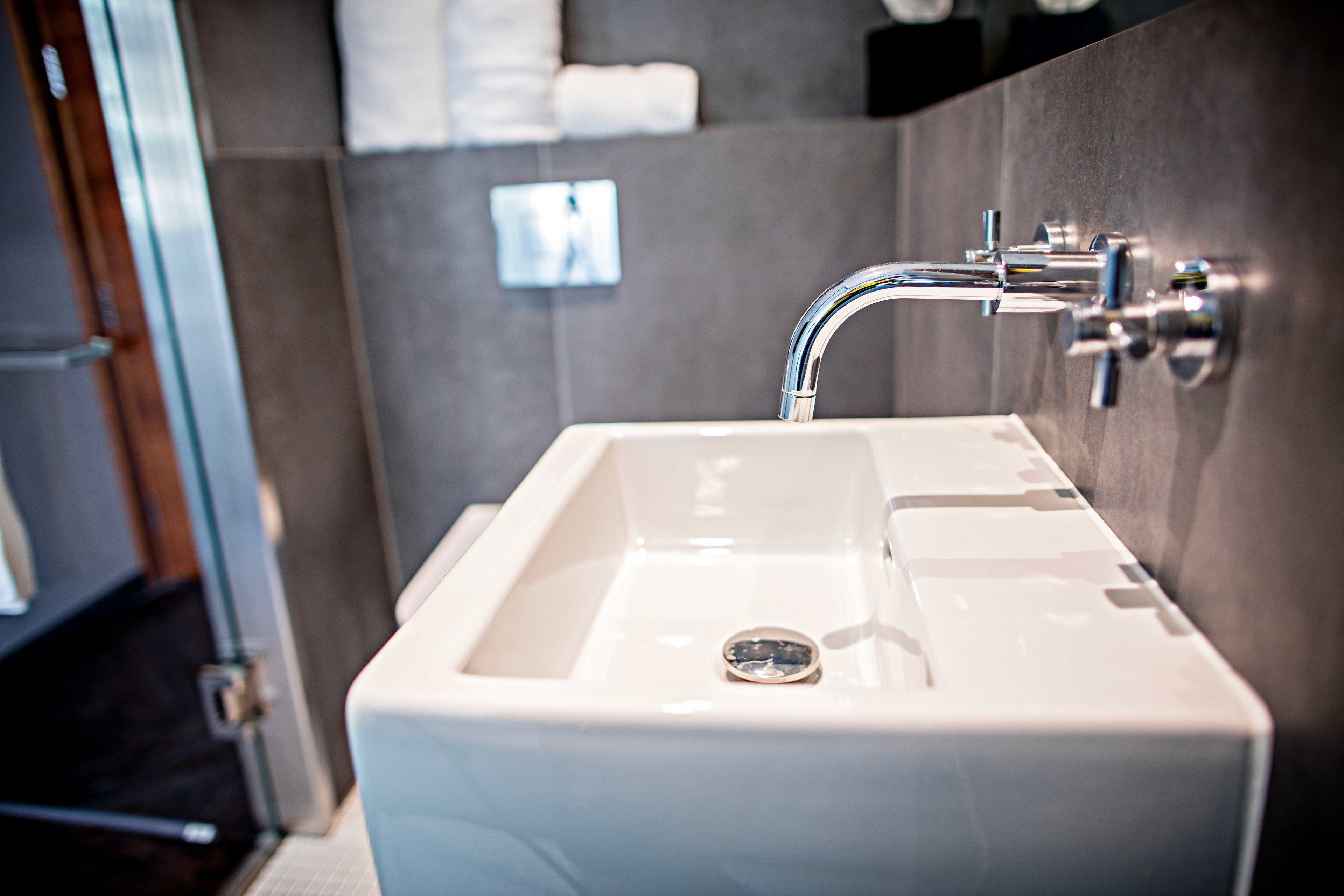 A modern bathroom with a white sink, chrome faucet, and a mirror above it.