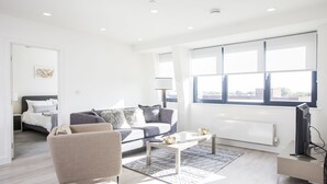 A modern living room with a sofa, armchair, coffee table, and a TV.
