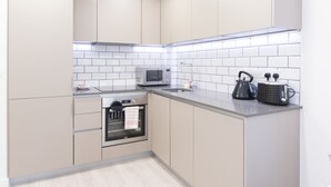 A modern kitchen with white cabinets, a microwave, a kettle, and a toaster on the countertop.