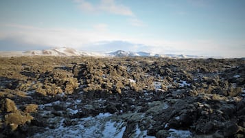A rocky landscape with snow patches and distant mountains.