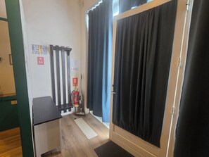A small room with a desk, a fire extinguisher, and a door with black curtains. - Reykjanes Guesthouse (Grindavik)