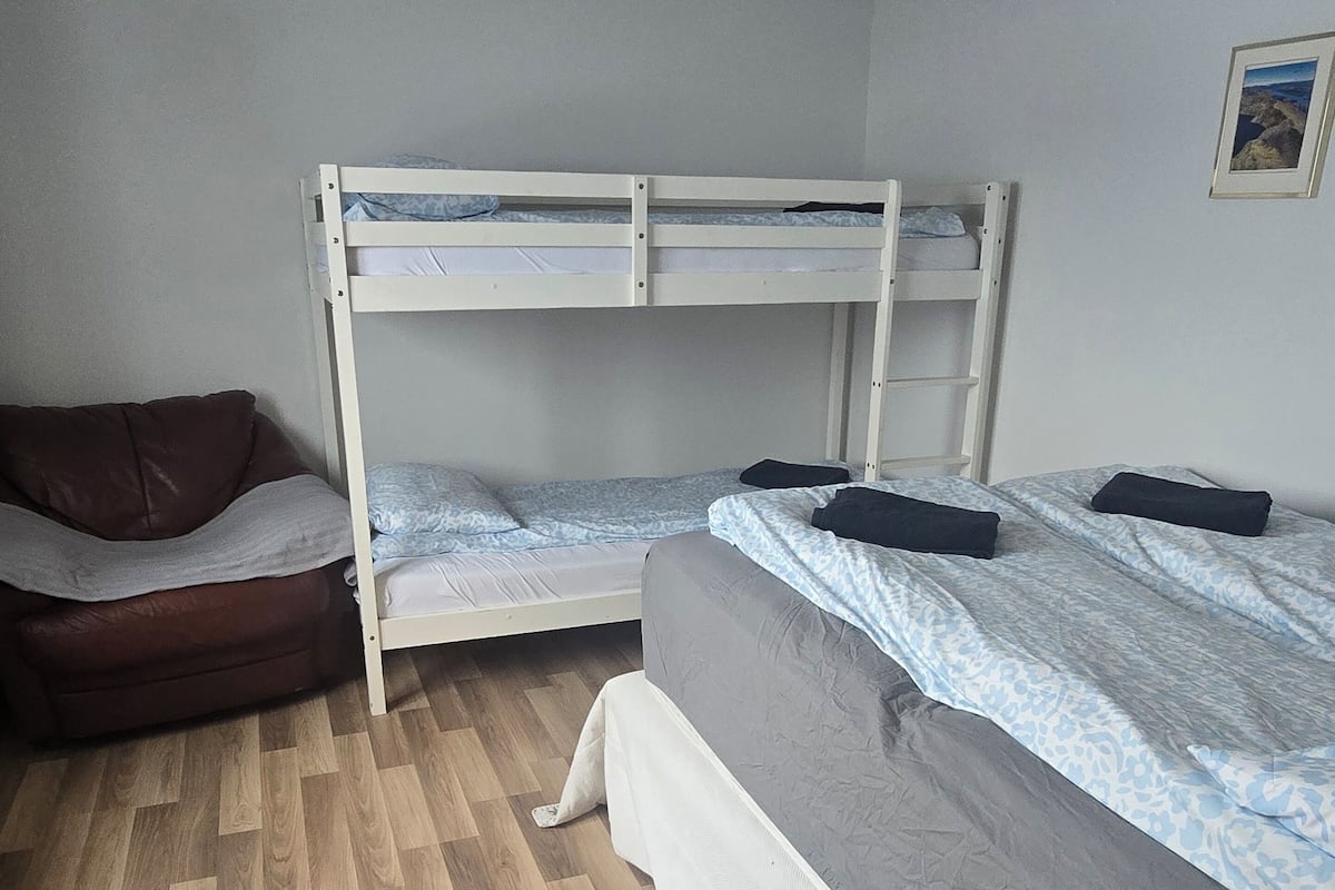 A room with two bunk beds, a sofa, and a wooden floor.