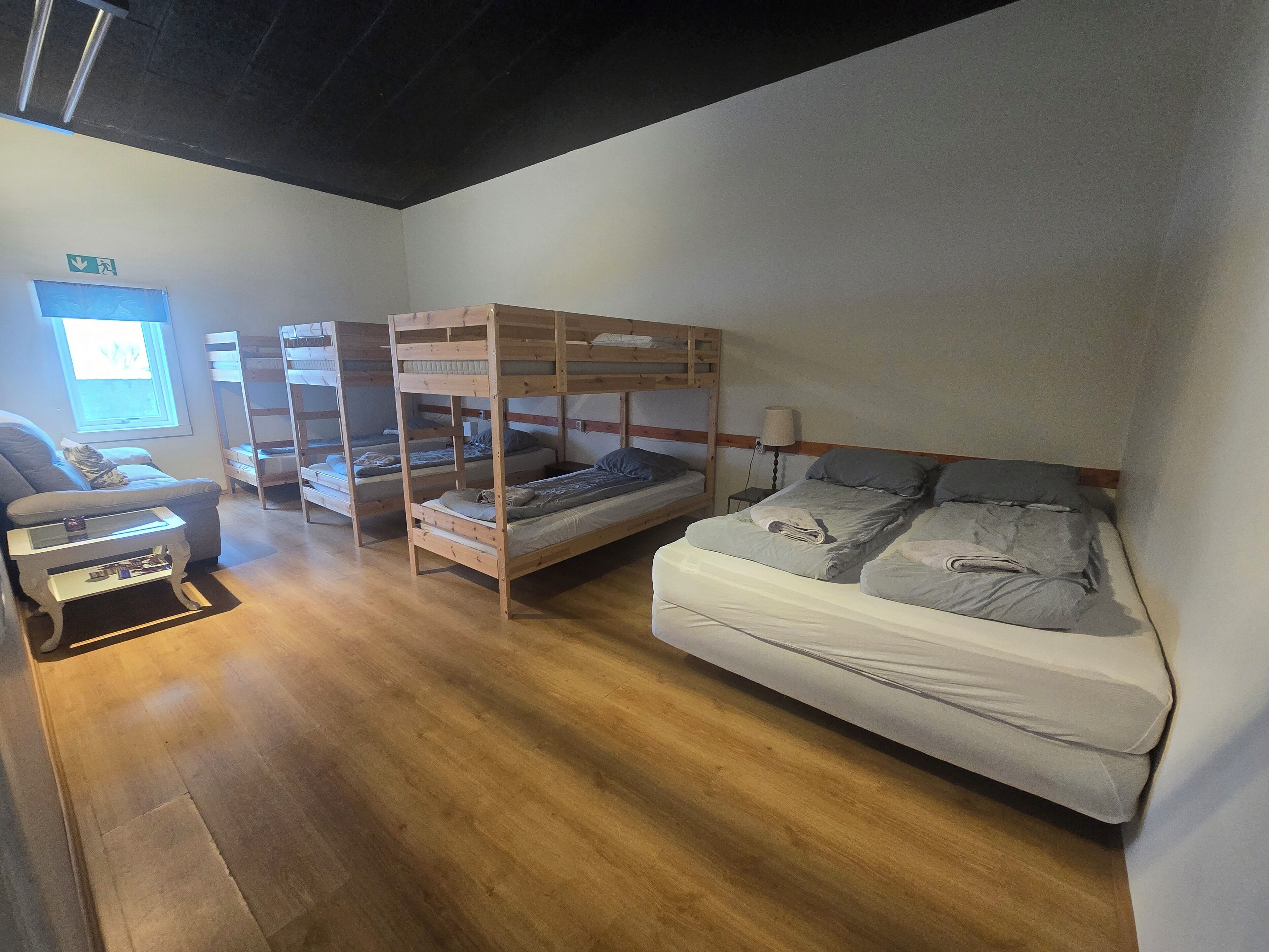 Una habitación con literas, un sofá, una mesita y una lámpara.