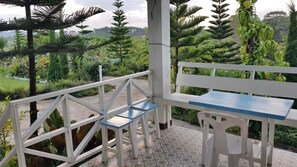 A covered outdoor seating area with a white bench and a small table, surrounded by lush greenery and a patterned floor. - Tonkaew Khaokho Resort (Khao Kho)