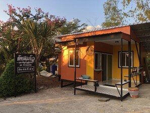 A small, single-story building with a yellow exterior and a brown roof. There is a sign with Thai text and a phone number. - Tonkaew Khaokho Resort (Khao Kho)