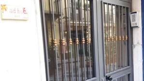 A metal gate with vertical bars and decorative elements, a sign with partially visible text, and a building facade with balconies. - Ad Hoc Rooms (Palermo)