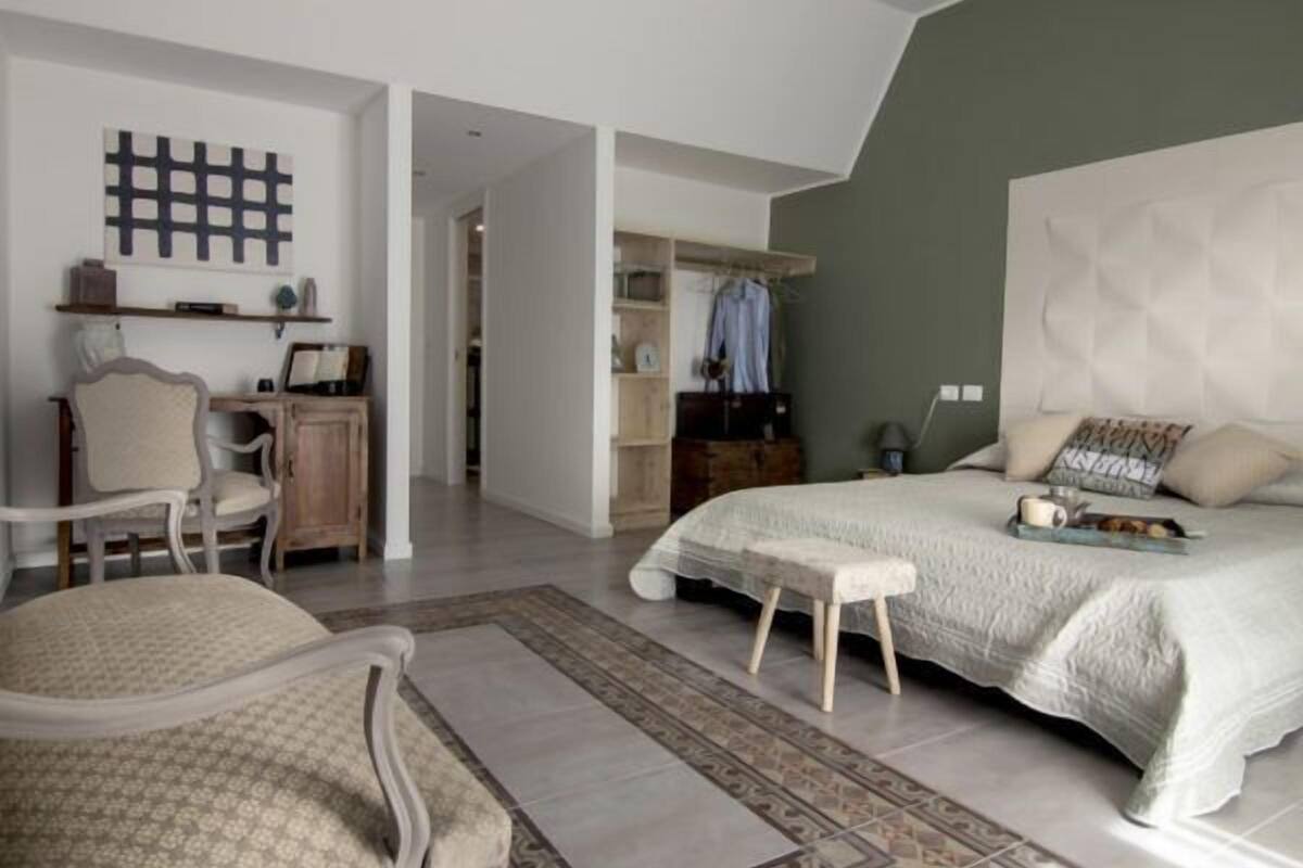 A spacious bedroom with a large bed, a desk, and a wardrobe.