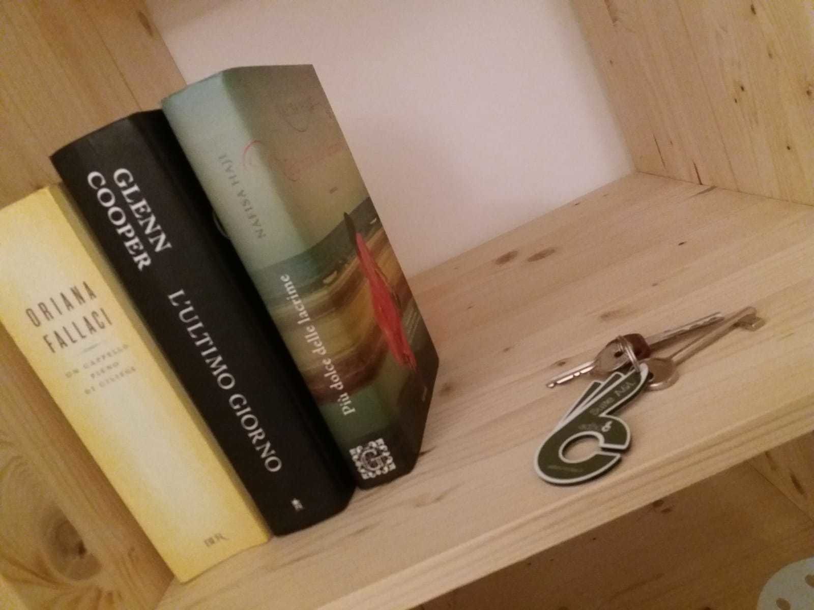 Ein Holzregal mit drei Büchern und einem Schlüsselanhänger.