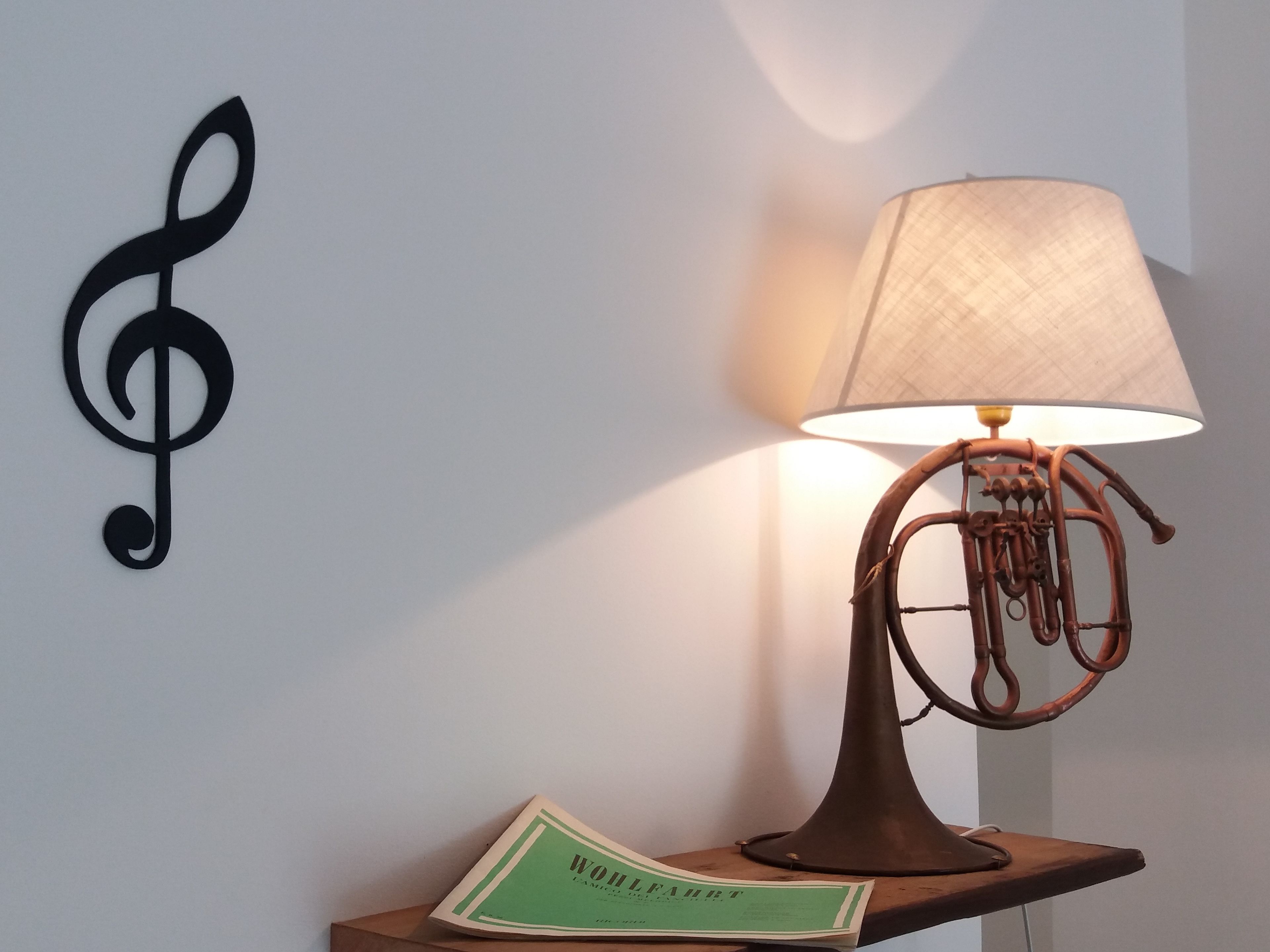 Een wandlamp met een uniek ontwerp, een decoratieve notenbalk en een boek getiteld 