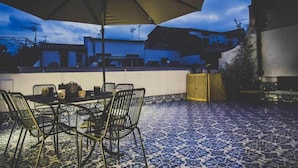 An outdoor patio with a table and chairs, a large umbrella, and a patterned floor. - Ad Hoc Rooms (Palermo)
