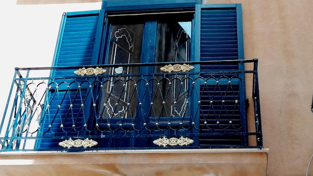 A balcony with blue shutters and ornate metal railings. - Mirabilia Arab House (Mazara del Vallo)