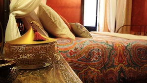 A traditional Moroccan bed with a colorful patterned bedspread, a brass lantern with a tassel, and a white canopy. - Mirabilia Arab House (Mazara del Vallo)