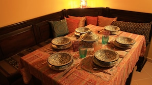 A dining table set with traditional Moroccan plates, glasses, and cutlery, surrounded by a patterned tablecloth. - Mirabilia Arab House (Mazara del Vallo)