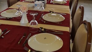 A long dining table set for a meal with chairs on both sides, overlooking a body of water. - Otel Diyojen (Sinop)