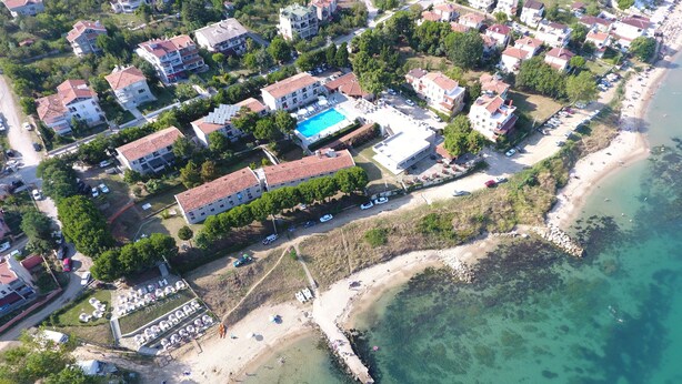 An aerial view of a coastal residential area with multiple apartment buildings, a swimming pool, and a beach. - Otel Diyojen (Sinop)