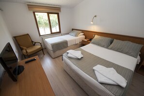 A hotel room with two single beds, a sofa, a desk with a remote control, and a window with blinds. - Otel Diyojen (Sinop)