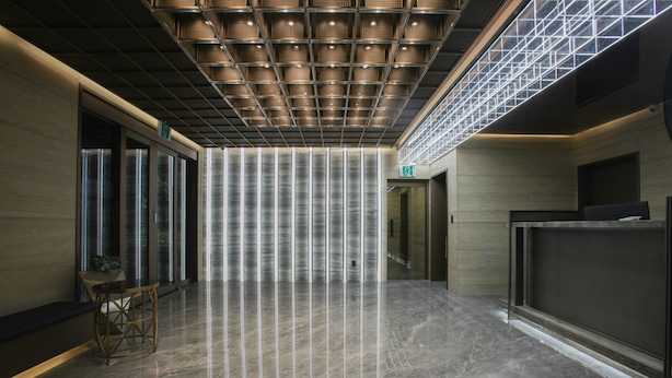 Un hall d’entrée moderne avec un plafond haut, une colonne centrale et un comptoir d’accueil.