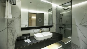 Une salle de bain moderne avec un lavabo blanc, un plan de toilette noir et une douche à parois de verre.