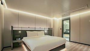 Une chambre d’hôtel moderne avec un grand lit, une table de chevet avec une lampe et une armoire intégrée.