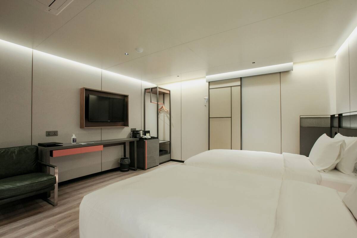 Een moderne hotelkamer met een bed, bureau, televisie en een kledingkast.