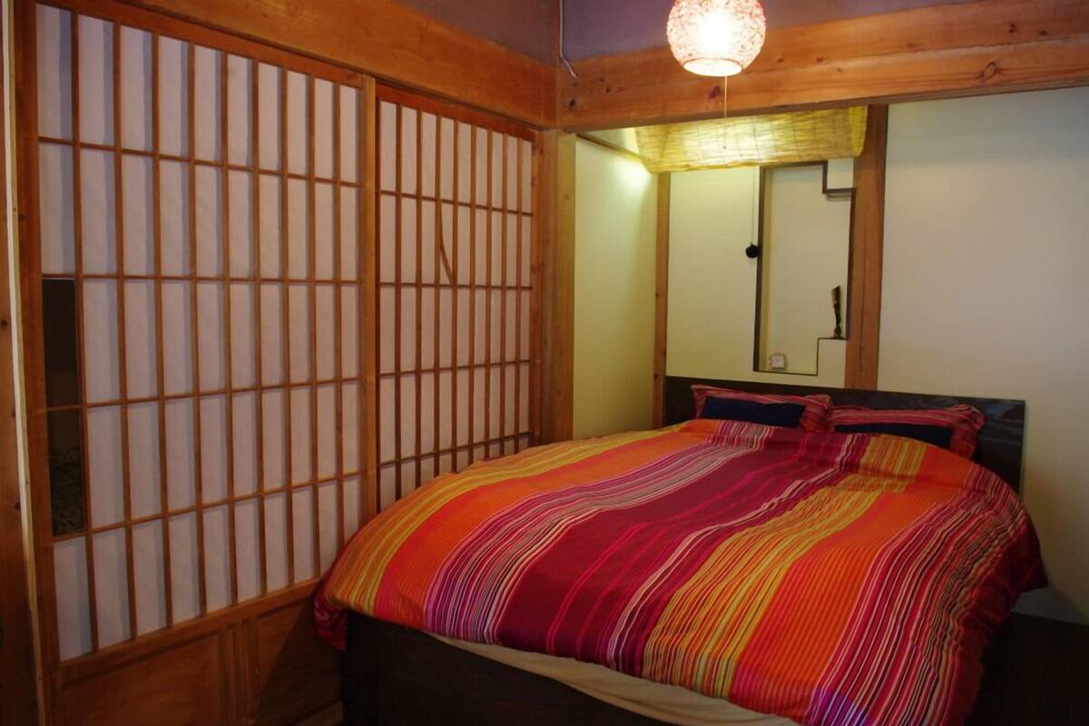A room with a bed, wooden sliding doors, and a mirror on the wall.