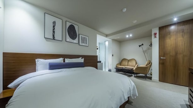 A hotel room with a large bed, a sofa, a desk, and a wardrobe. - Boutique Hotel HAVE (Busan)
