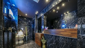 A modern reception area with marble walls and a wooden reception desk. - Boutique Hotel HAVE (Busan)