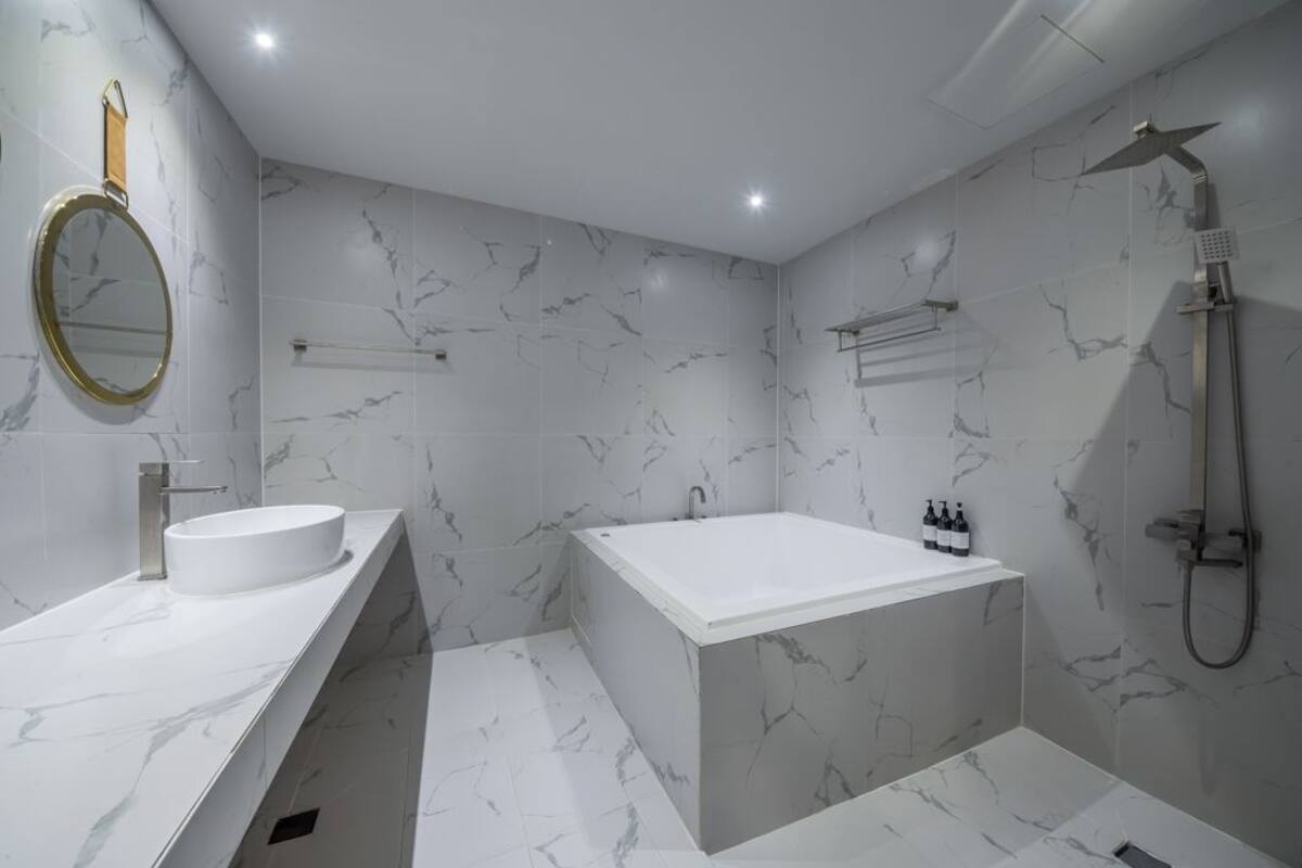 A modern bathroom with a marble vanity, a freestanding bathtub, and a shower area.
