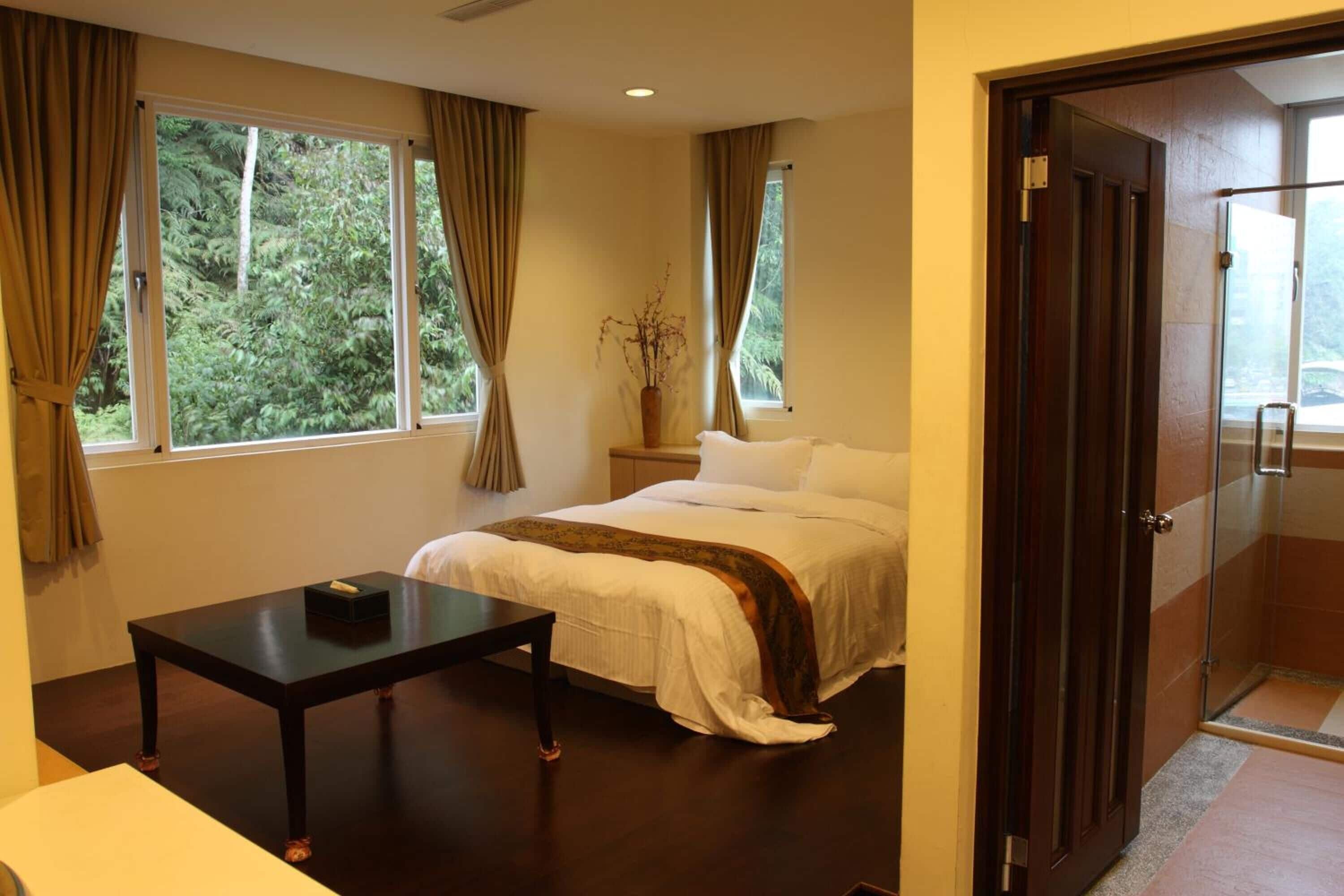 A bedroom with a bed, a bedside table, and a window with curtains.