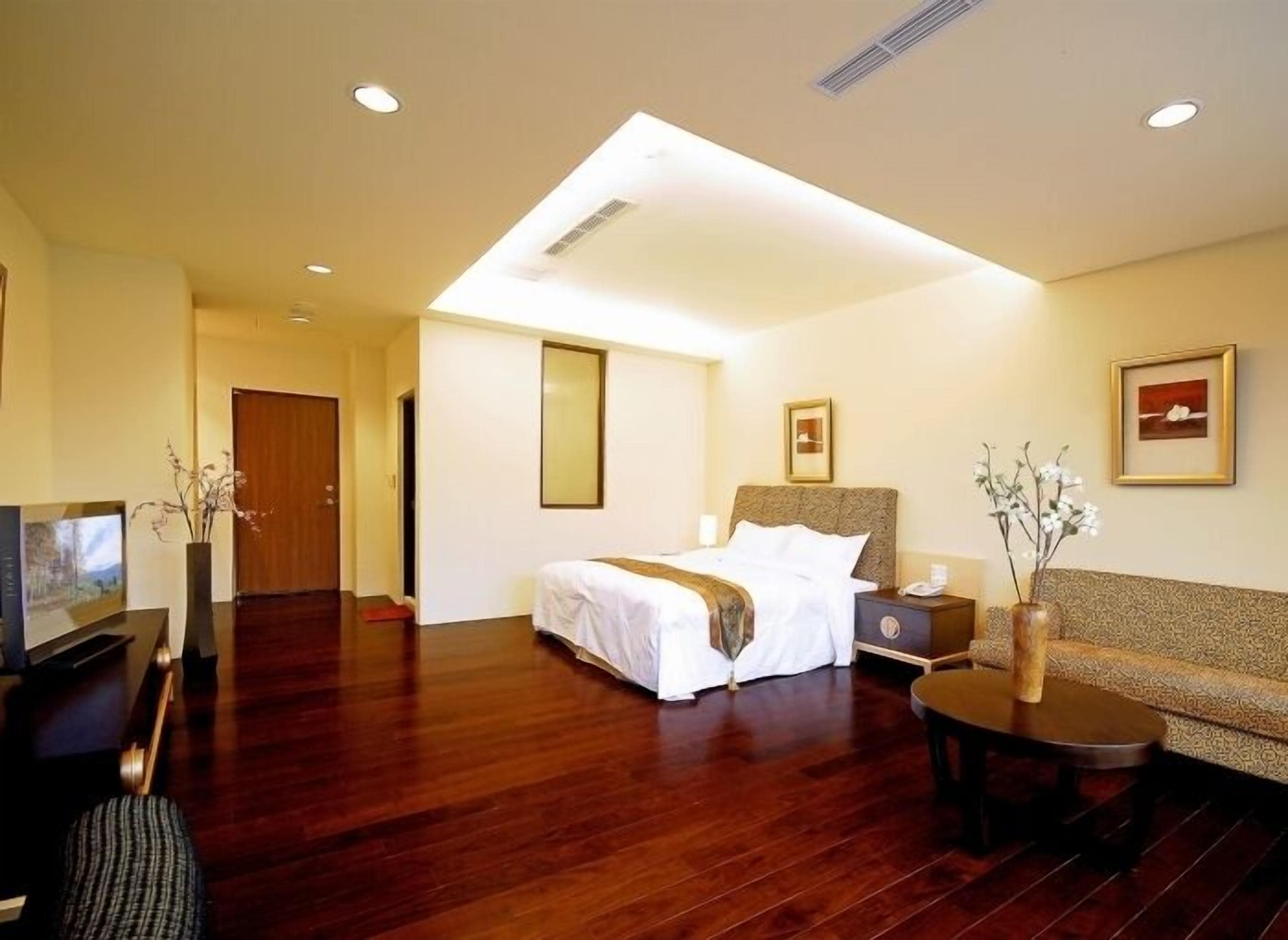 A hotel room with a bed, a sofa, a TV, and a desk.