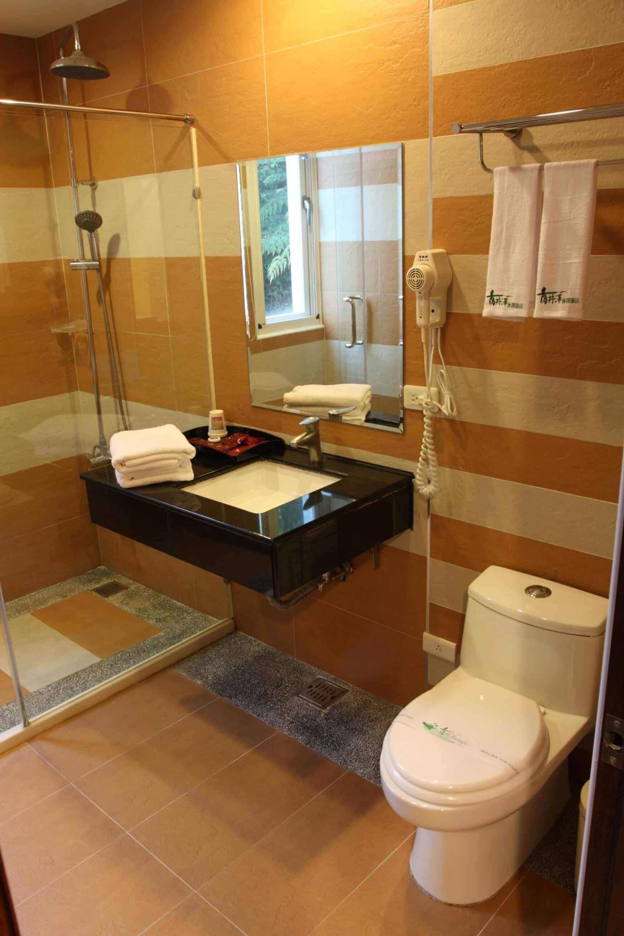 A bathroom with a glass-enclosed shower, a black vanity with a sink, a toilet, and a towel rack with towels.