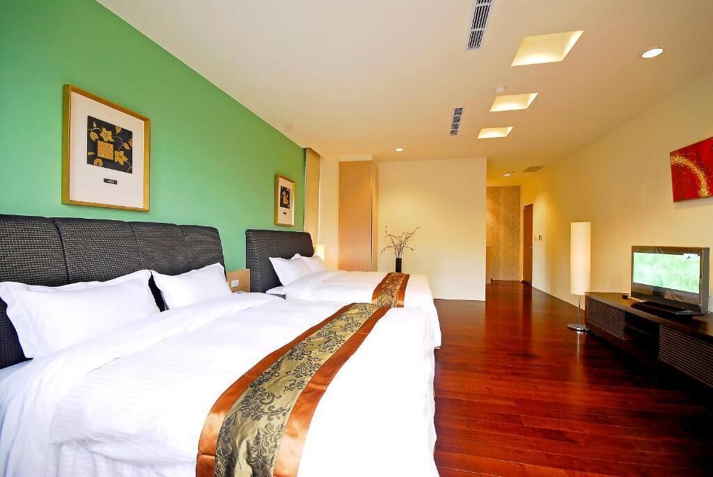 A hotel room with a large bed, a television, and a green wall.