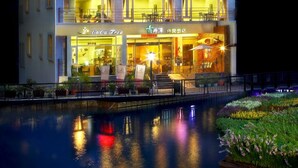 Un hotel de varios pisos con un letrero, balcones y una piscina reflejante.