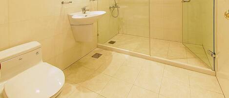 Un baño moderno con inodoro, lavamanos y cabina de ducha de vidrio.