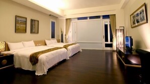 Habitación de hotel con dos camas, televisión, escritorio y un ventanal grande.