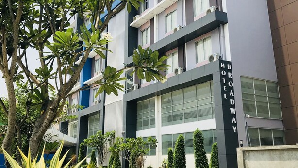 Un hotel de varios pisos con un diseño moderno, con balcones, ventanas amplias y un jardín bien cuidado.