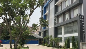 Un hotel moderno con una estructura de varios pisos, un acceso cubierto y un camino ajardinado.