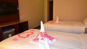 Dos camas de hotel con pétalos de rosa y una toalla con forma de cisne.
