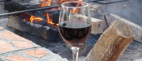 A glass of red wine on a brick surface near a fire pit.