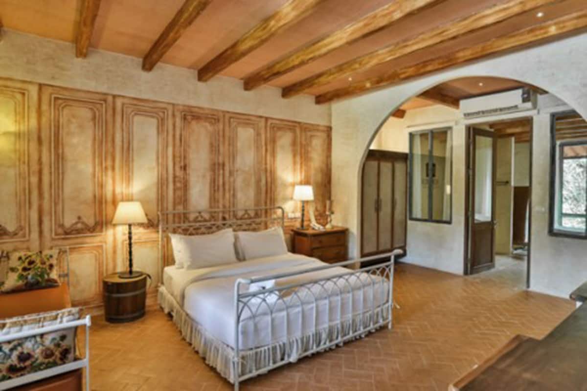 A bedroom with a bed, nightstands, a lamp, and a wooden ceiling.