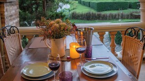 An outdoor dining area with a view of a landscaped garden and mountains. - La Toscana Resort (Suan Phueng)