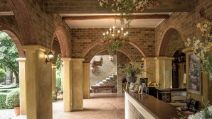 A spacious lobby with a high ceiling, brick arches, and a central staircase. - La Toscana Resort (Suan Phueng)