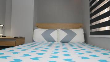 A bedroom with a bed, a nightstand, and a lamp.