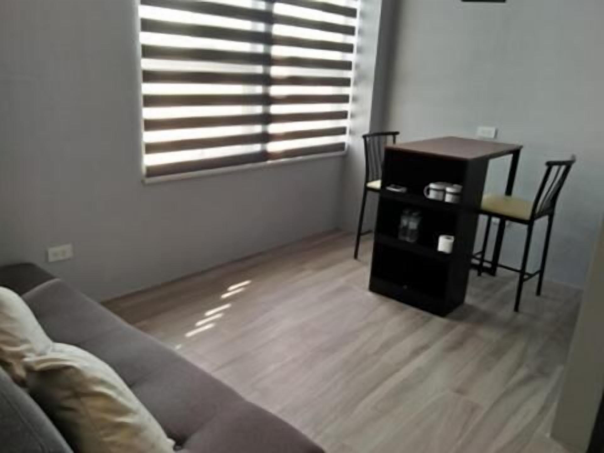 A living room with a sofa, a small table with chairs, and a bookshelf.