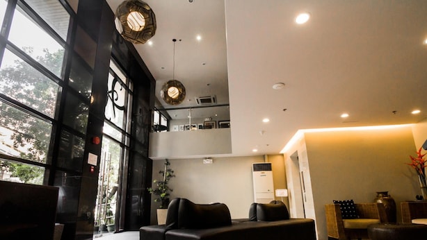 Un intérieur moderne avec un canapé noir, un coin repas et une grande fenêtre donnant sur la verdure.